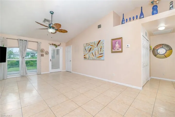 Spare room with vaulted ceiling, a ceiling fan, and light tile patterned flooring