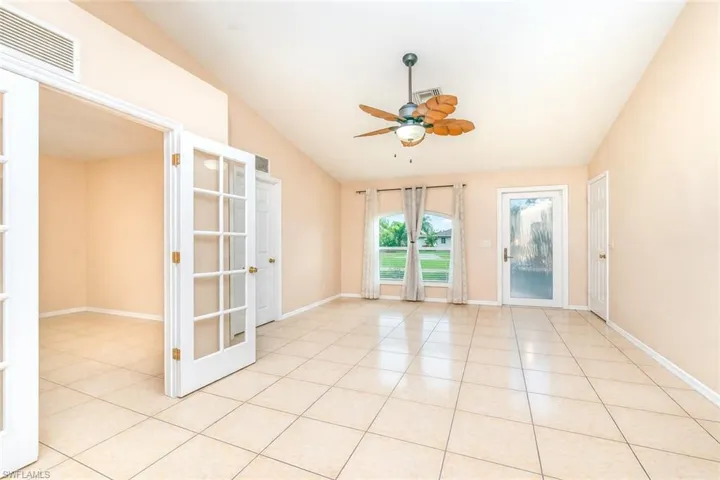 Empty room with a ceiling fan, vaulted ceiling, and light tile patterned floors