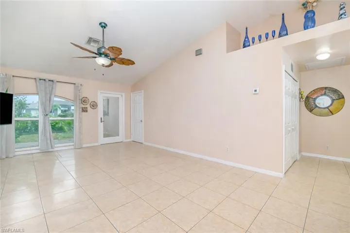 Unfurnished room with lofted ceiling, a ceiling fan, and light tile patterned flooring