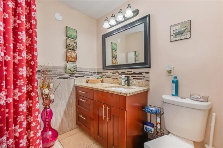 Bathroom with vanity, light tile patterned flooring, and decorative backsplash