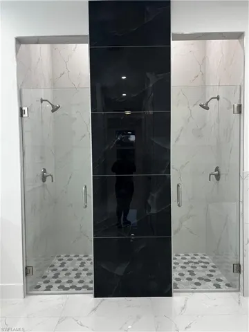 Bathroom with a marble finish shower and marble look tile flooring