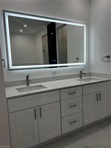 Bathroom with light marble finish floors, double vanity, a marble finish shower, and recessed lighting