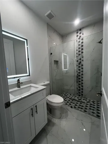 Full bathroom with vanity, light marble finish flooring, and a marble finish shower