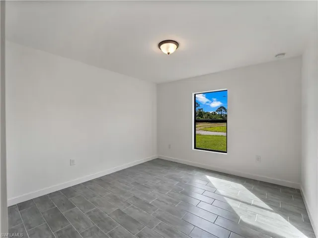 Spare room featuring baseboards and wood finish floors