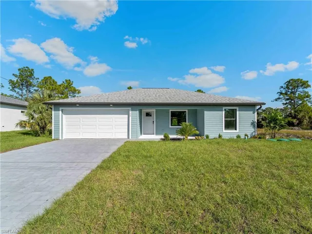 Ranch-style house featuring a front lawn, decorative driveway, an attached garage, and covered porch