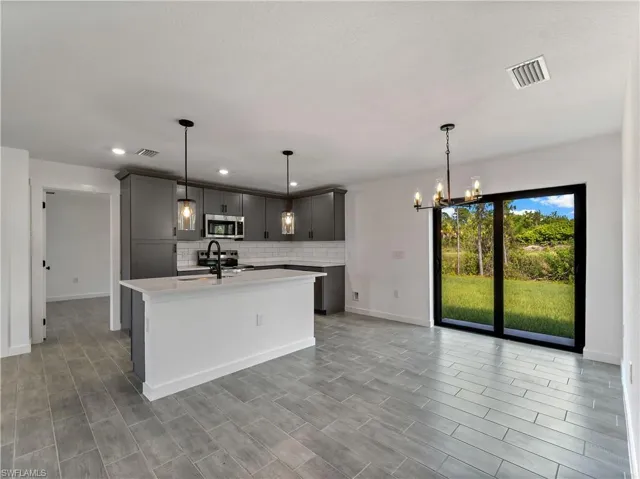Kitchen featuring gray cabinetry, backsplash, decorative light fixtures, stainless steel appliances, and recessed lighting