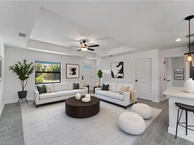 Virtually Staged  Living room featuring a raised ceiling, wood finish floors, ceiling fan, and recessed lighting