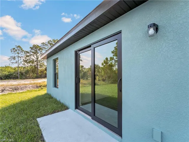 View of property exterior featuring stucco siding, a patio area, and a lawn