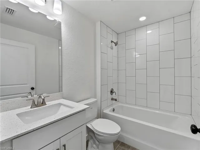 Full bath with a textured wall, shower / washtub combination, and vanity