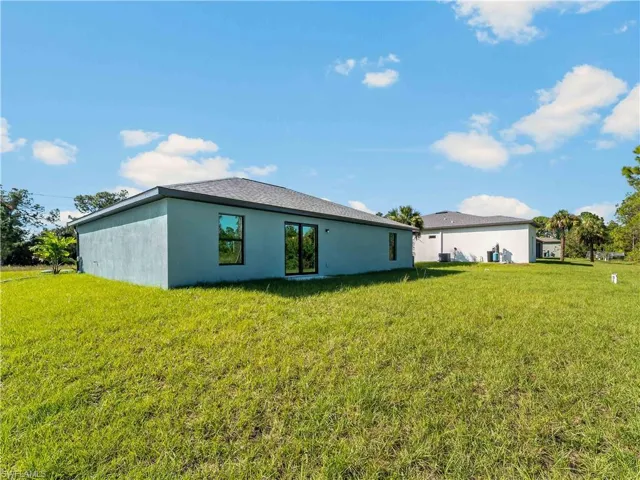 Rear view of property with a yard and stucco siding