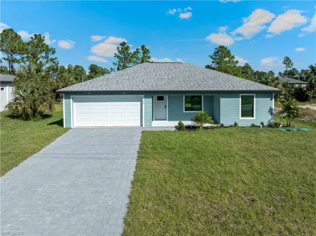 Ranch-style house featuring decorative driveway, roof with shingles, a front yard, and an attached garage