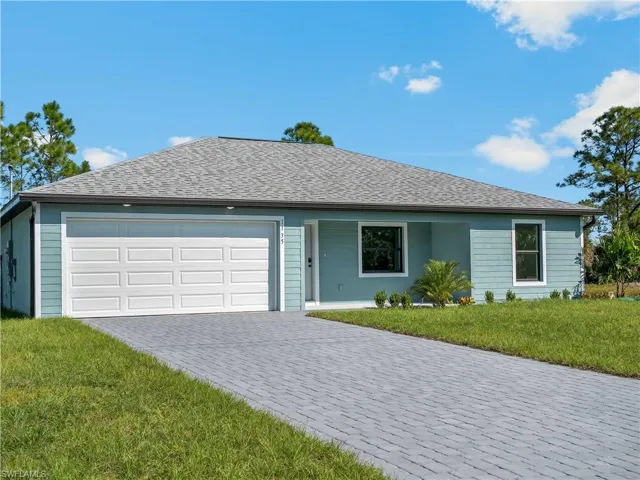 Ranch-style home featuring a front lawn, decorative driveway, and roof with shingles