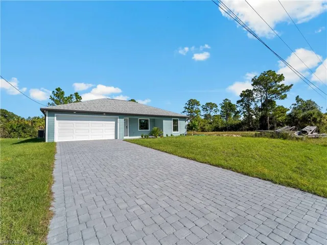 Ranch-style home with a front lawn, decorative driveway, and an attached garage