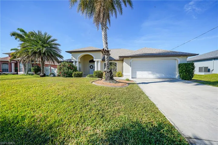 View of front of house with central AC unit, a garage, and a front lawn