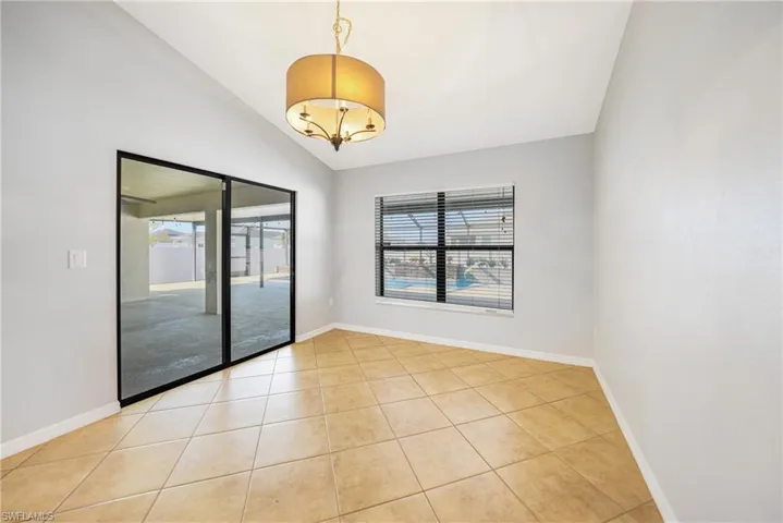 Spare room featuring a notable chandelier, light tile patterned floors, and vaulted ceiling