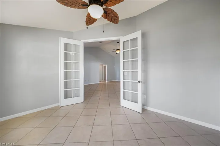 Tiled spare room featuring french doors and vaulted ceiling