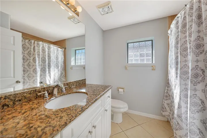 Bathroom with toilet, vanity, and tile patterned floors