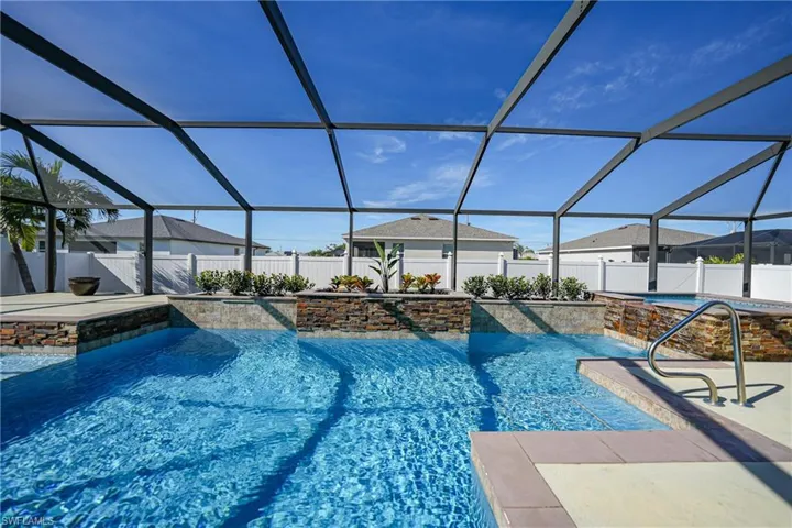 View of swimming pool with pool water feature, glass enclosure, and a patio area