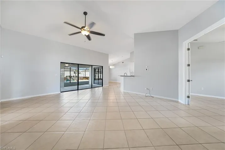Unfurnished living room featuring ceiling fan, light tile patterned floors, and lofted ceiling