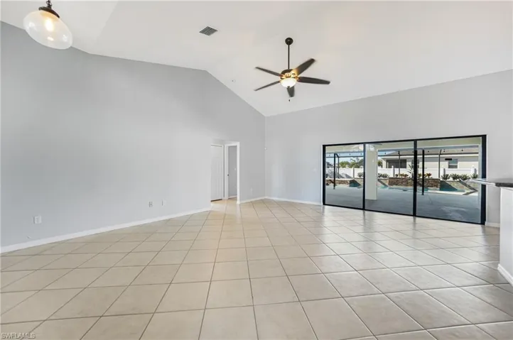 Tiled spare room with ceiling fan and high vaulted ceiling
