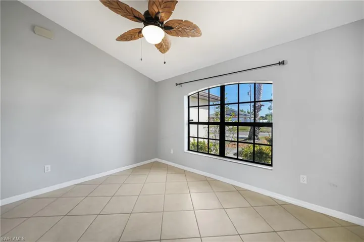 Unfurnished room featuring ceiling fan, light tile patterned floors, and vaulted ceiling