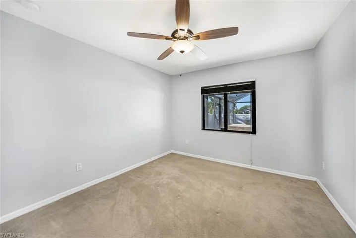 Carpeted empty room featuring ceiling fan