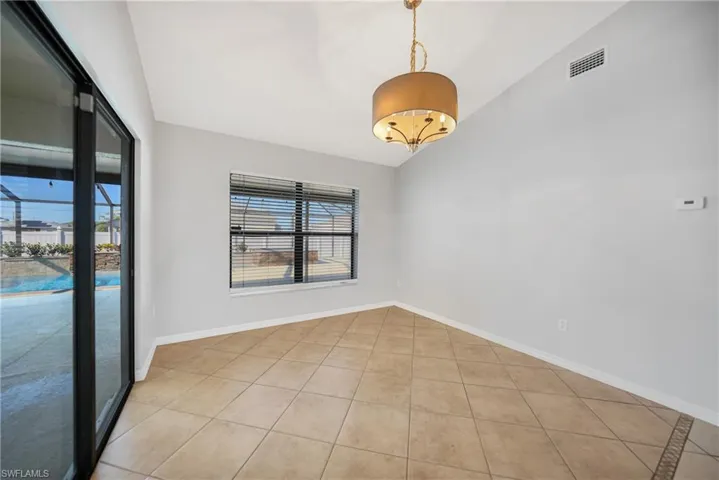 Unfurnished room featuring light tile patterned floors and lofted ceiling