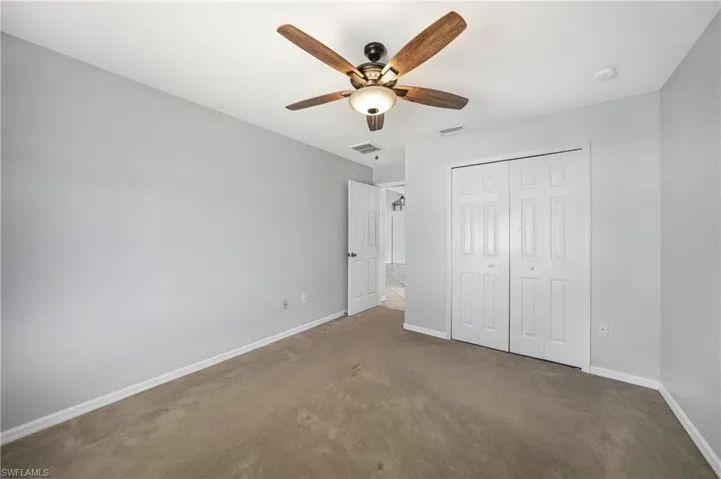 Unfurnished bedroom with ceiling fan, carpet floors, and a closet