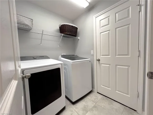 Laundry room with washer and dryer and light tile patterned floors