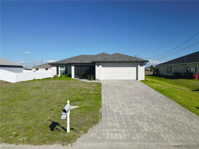 Single story home with a front yard, stucco siding, decorative driveway, and an attached garage