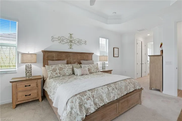 Bedroom featuring ornamental molding, a closet, light colored carpet, a ceiling fan, and a raised ceiling