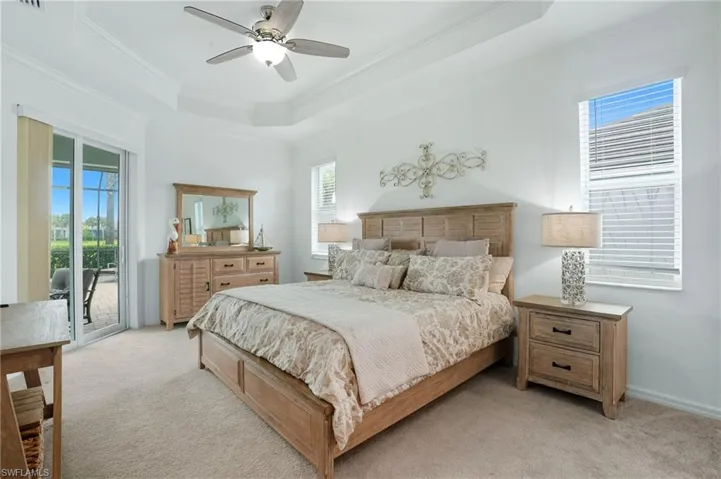 Bedroom with a raised ceiling, crown molding, access to outside, carpet floors, and a ceiling fan