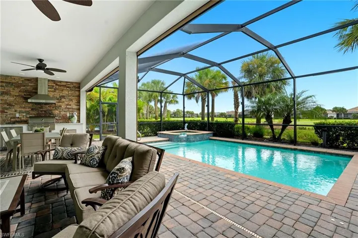 View of pool with an outdoor living space, exterior kitchen, a patio, a sunroom, and a pool with connected hot tub