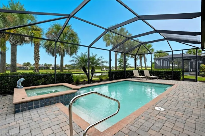 View of pool featuring a pool with connected hot tub, glass enclosure, a sunroom, and a patio
