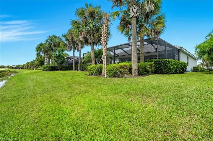 View of grassy yard featuring a sunroom and glass enclosure