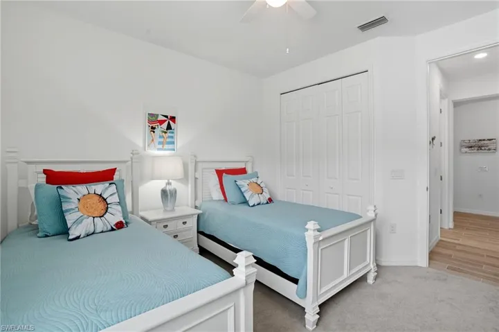 Bedroom with light colored carpet, a closet, and a ceiling fan