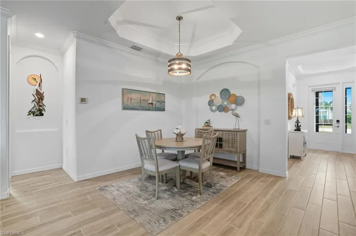 Dining space with ornamental molding, wood tiled floors, and a tray ceiling