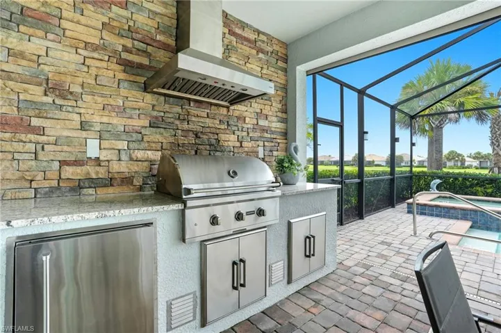View of patio with a sunroom, a lanai, a pool with connected hot tub, exterior kitchen, and a residential view