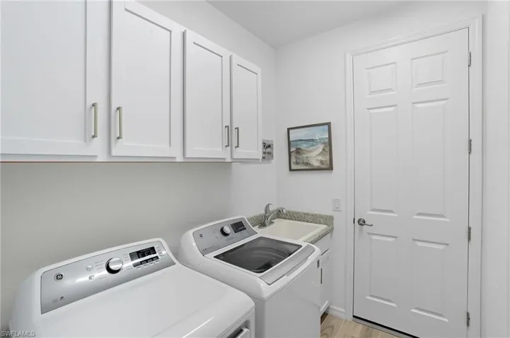Laundry room featuring light wood-type flooring, washing machine and dryer, and cabinet space