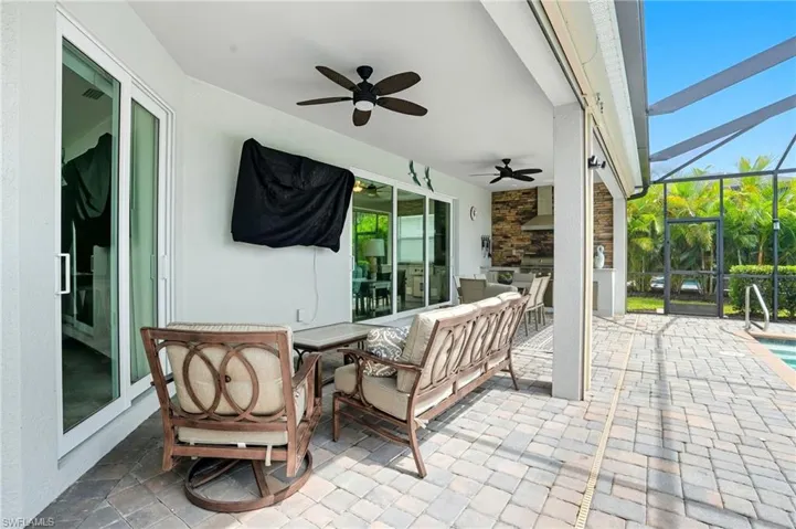 View of patio / terrace featuring a sunroom, outdoor dining area, a ceiling fan, exterior kitchen, and a lanai