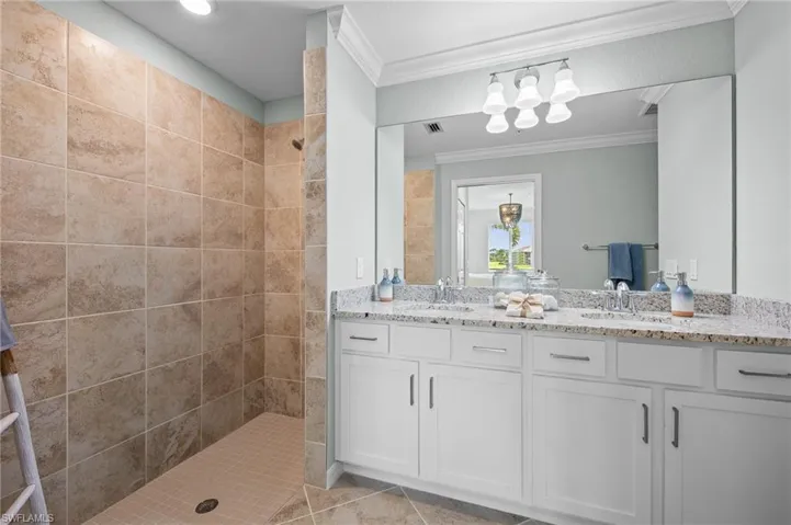 Full bathroom with crown molding, a walk in shower, double vanity, and tile patterned floors
