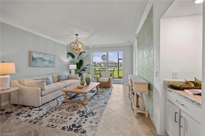 Living room with ornamental molding, light tile patterned floors, and a chandelier
