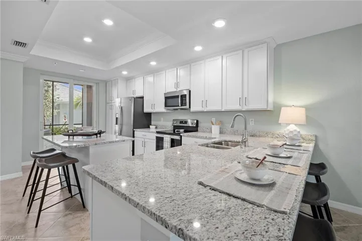 Kitchen featuring appliances with stainless steel finishes, crown molding, a tray ceiling, a kitchen bar, and a center island