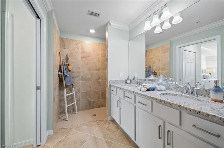 Bathroom with crown molding, double vanity, connected bathroom, walk in shower, and tile patterned flooring