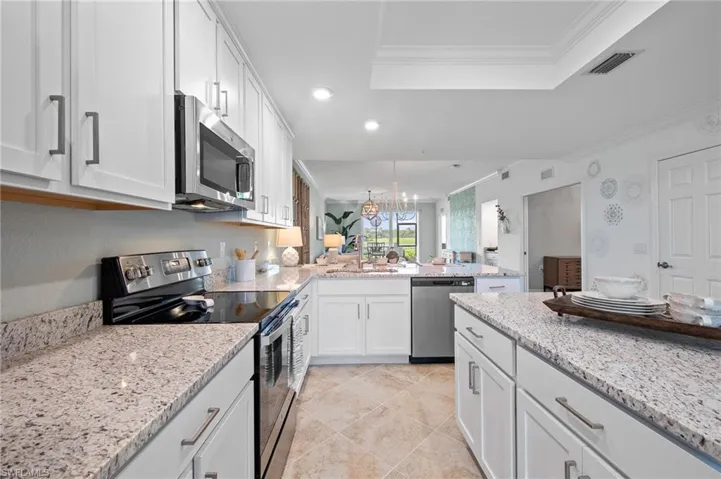 Kitchen featuring stainless steel appliances, a raised ceiling, recessed lighting, a peninsula, and white cabinets