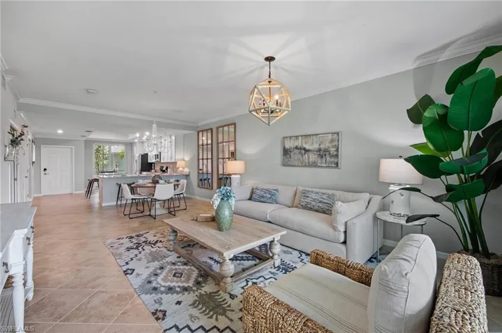 Living area featuring a chandelier, ornamental molding, and light tile patterned floors