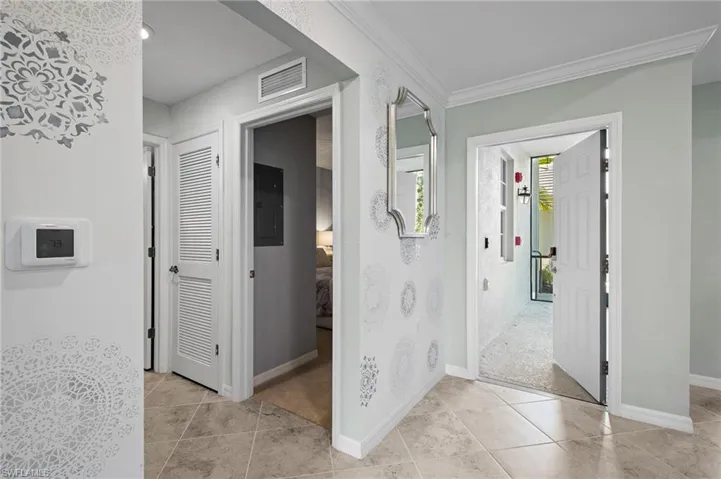 Corridor featuring electric panel, light tile patterned floors, and ornamental molding