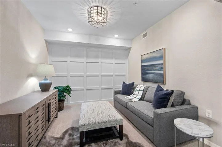 Living room with carpet floors, recessed lighting, and a textured wall