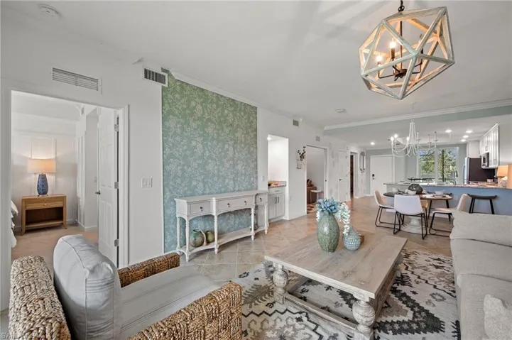 Living room with a chandelier, ornamental molding, and light tile patterned floors