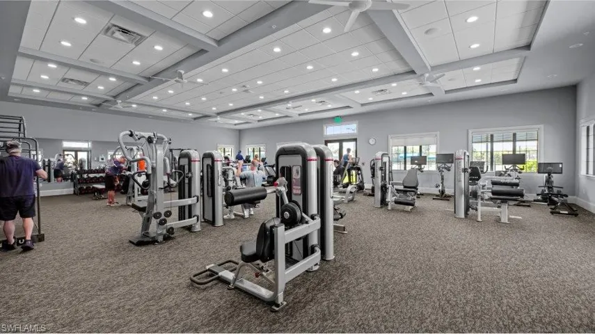Exercise room with recessed lighting, healthy amount of natural light, a towering ceiling, coffered ceiling, and beamed ceiling